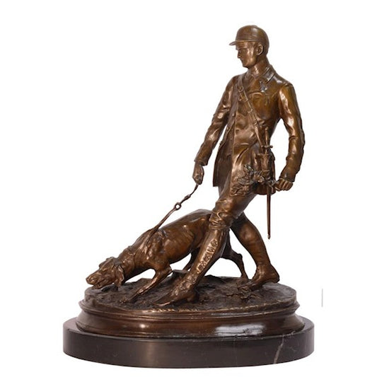 Een bronzen beeld van een jager met zijn jachthond die snuffelt aan de grond op zoek naar een nieuwe prooi