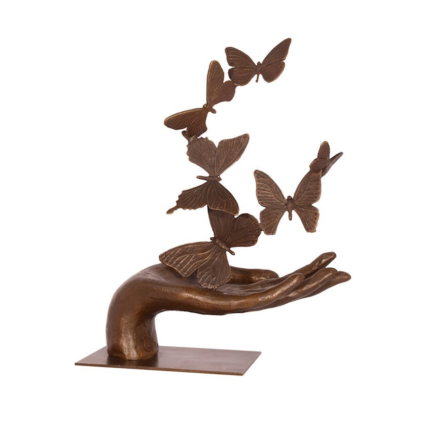 Bronzen beeld van een hand waar vlinders boven vliegen en fladderen 